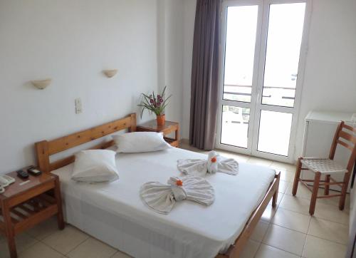 海若克利欧波塞冬酒店的一间卧室配有一张带白色床单和弓的床铺