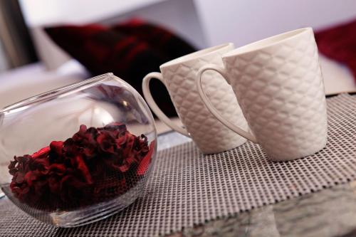 尼亚卢卡Luxory D-Rooms的两个咖啡杯和一碗红玫瑰