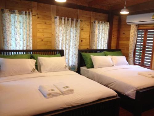 安帕瓦农尼邦康提度假村的配有木墙和窗户的客房内的两张床