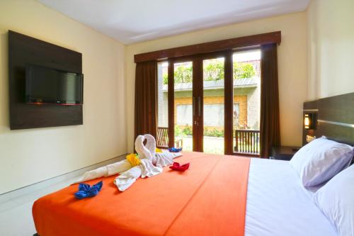 勒吉安Gempita House Bali的一间卧室配有带毛巾的床和平板电视