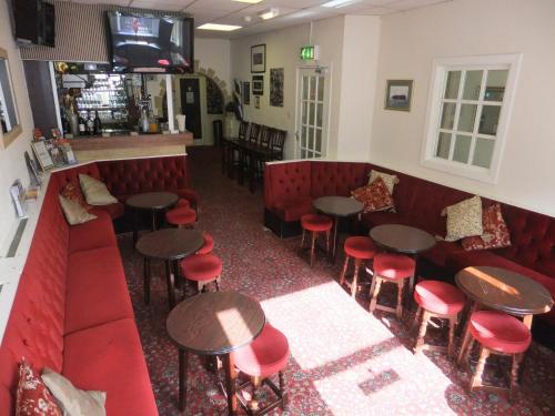 布莱克浦查恩利金住宿加早餐旅馆的餐厅设有红色的摊位、桌子和红色的凳子