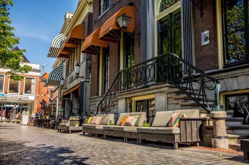吕伐登Boutique Hotel Catshuis的坐在建筑物旁的街道上的一排长椅