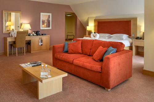 阿克菲尔德东萨西克斯国家酒店，高尔夫度假村&SPA的客厅配有红色的沙发和床。