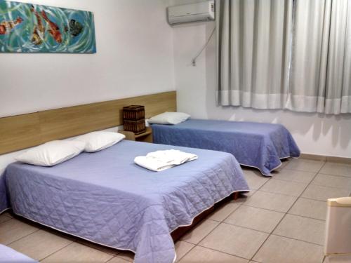 瓜拉派瑞Hotel Diamantina - By UP Hotel - em Guarapari的紫色床单的客房内的两张床