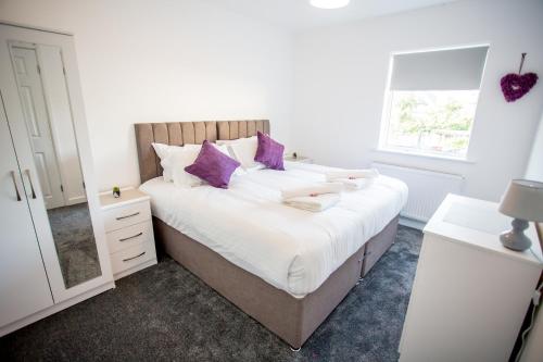 塔姆沃思Lovely 3 Bedroom House - Close to all attractions - Free Parking的一间卧室配有一张带紫色枕头的大床