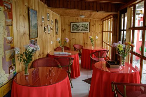 洛斯比洛斯Hostal El Conquistador的一间设有红色桌子和椅子的房间,里面种着鲜花