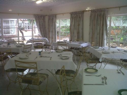 RuwaNora Valley Lodge的配有白色桌椅和窗户的客房