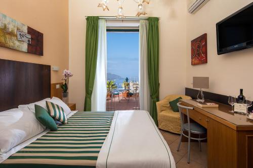 陶尔米纳Hotel "La Pensione Svizzera"的一间卧室配有一张床、一张书桌和一个窗户。