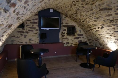 Saint-YbardHôtel Saint-Roch, The Originals Relais的洞穴内的房间,配有桌椅和电视