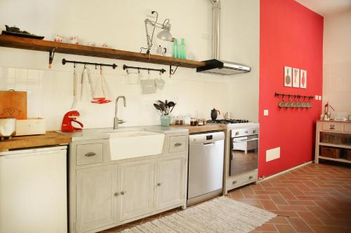 阿罗纳Agriturismo Biomatto的厨房配有白色橱柜和红色墙壁