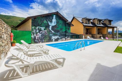 Caboalles de Abajo阿必瑟田园公寓酒店的一个带2把躺椅的游泳池以及1栋房子