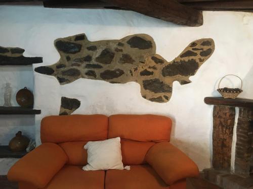 Jubrique卡萨拉蓬特度假屋的棕色的沙发,墙上有牛