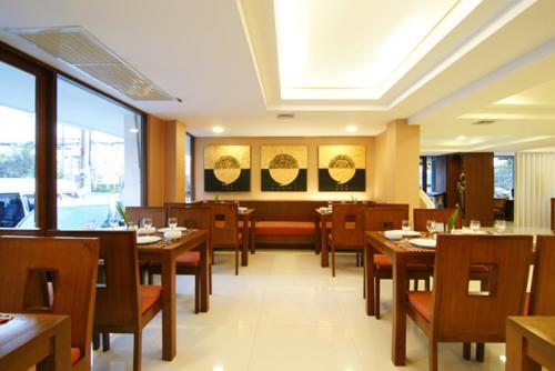 莱卡邦Mariya Boutique Hotel At Suvarnabhumi Airport的餐厅设有木桌、椅子和窗户。