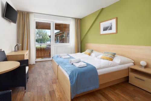 普雷迪尼维托Hotel Albatros的一间卧室配有一张床、一张桌子和一个窗户。