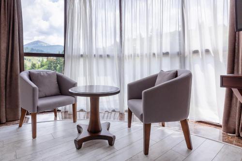 布克维卡帕洛萨酒店的一间设有两把椅子、一张桌子和一个窗户的房间