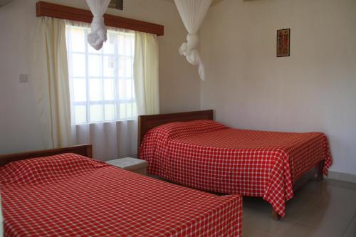 Ol KokweSandai Resort Lake Baringo的配有红色和白色床单的客房内的两张床
