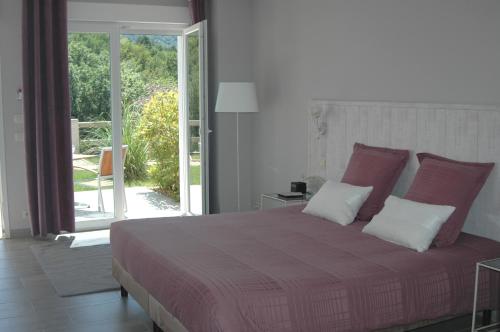 Belcastel-et-BucLes Jardins de Soulane B&B - Adults only的一间卧室设有一张大床和一个滑动玻璃门