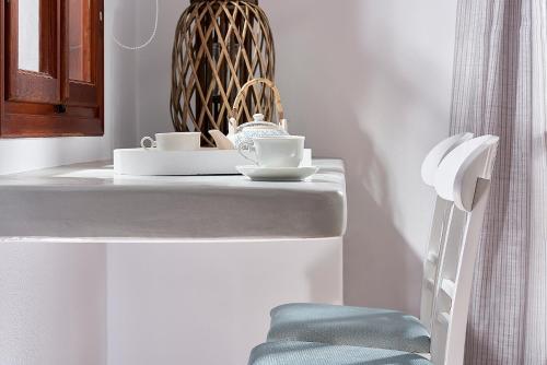 阿波罗尼亚Mirabeli Apartments & Suites的白色的柜台,带两个杯子和椅子