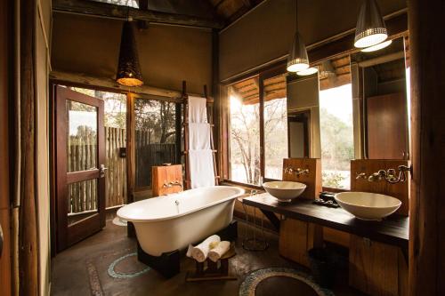 斯库库扎Rhino Post Safari Lodge的浴室配有两个盥洗盆和浴缸。