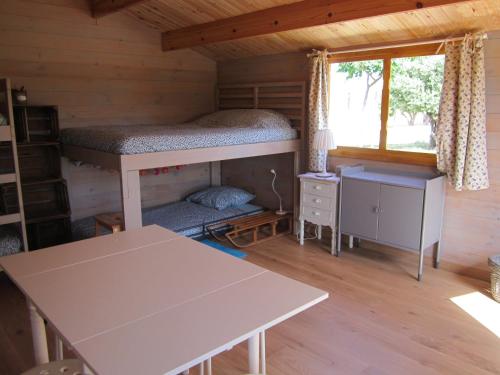 马藏La Grange de Campaulise - Camping à la ferme - Hébergements - Mont Ventoux的小屋内的一个房间,配有双层床和一张桌子