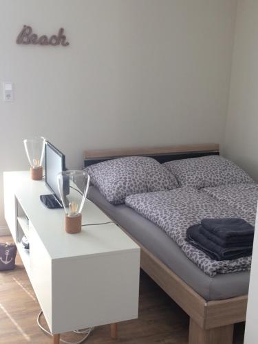 埃姆登„Lüttje Nüst“的一间卧室配有一张床和一张白色的书桌