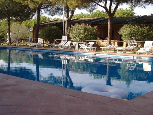 里奥托尔托Baia Etrusca Resort的一个带椅子和树木的游泳池以及一座房子