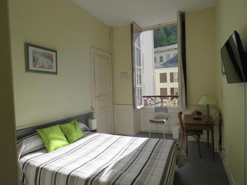欧波讷Hotel Richelieu的一间卧室配有一张带绿色枕头的床和一扇窗户