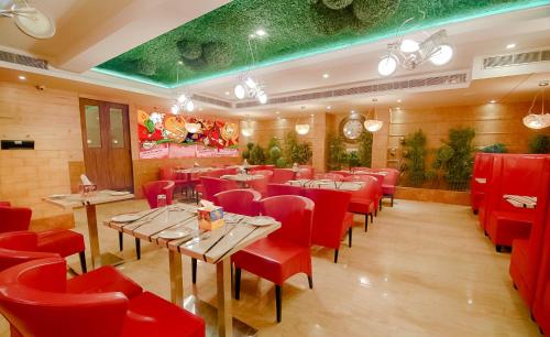 马图拉奥德拉神圣酒店的一间餐厅,房间内设有红色的椅子和桌子
