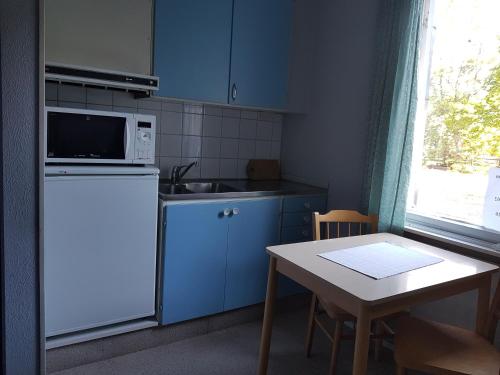 埃克勒Nalles Gästhem的厨房配有蓝色橱柜、桌子和微波炉