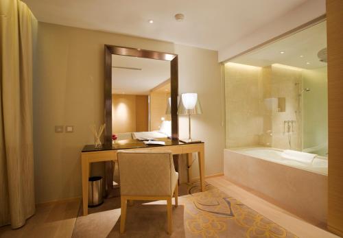 澳门City Viva Hotel Macau-Fomerly Hotel Million Dragon Macau的浴室配有带镜子的书桌和浴缸