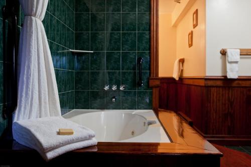 普莱西德湖镜湖度假&spa酒店的浴室配有浴缸、毛巾和淋浴