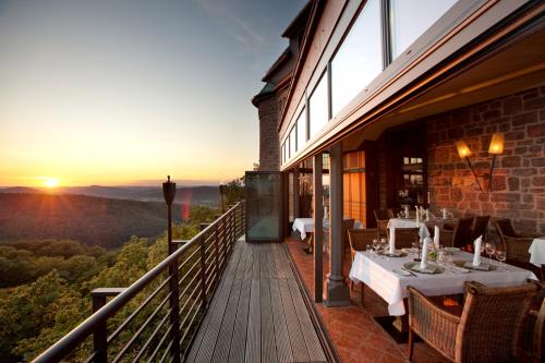 艾森纳赫瓦特堡罗曼蒂克酒店的餐厅在阳台上设有桌子,享有日落美景