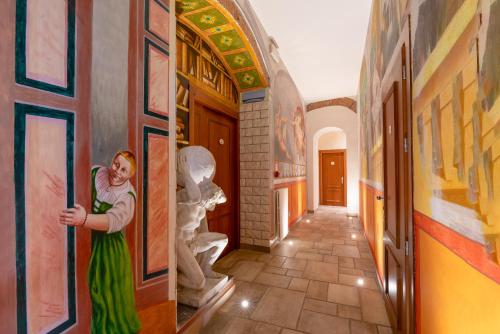 佛罗伦萨亚奇罗希酒店的站在走廊上墙上挂着绘画的女人