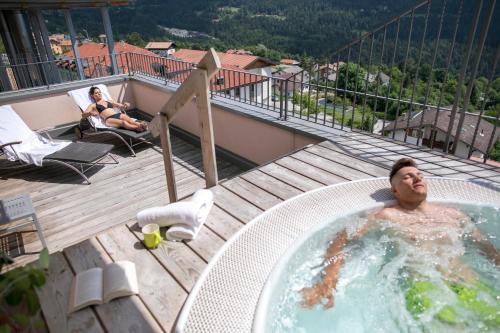 福尔加里亚Hotel Luna Bianca Folgaria的阳台上的热水浴池里的人