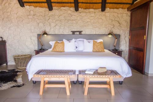 Manyoni Private Game ReserveLeopard Mountain Safari Lodge的一间卧室配有一张大床和两张长椅