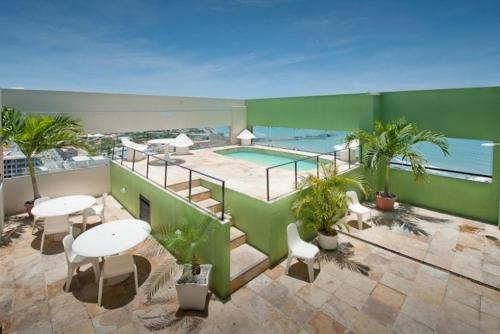福塔莱萨伊拉塞马旅游酒店的一个带桌椅的阳台和一个游泳池