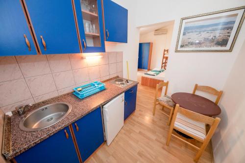 科兰Guesthouse Šime的厨房配有蓝色橱柜、水槽和桌子
