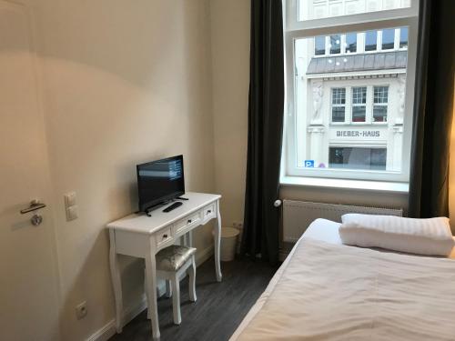 汉堡费姆奥豪巴福酒店的一间卧室配有一张床和一张书桌及电视