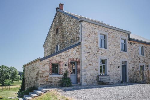 埃尔泽La croisée des champs, gîte entre Durbuy et La Roche en Ardenne的一座古老的石头房子,前面设有长凳