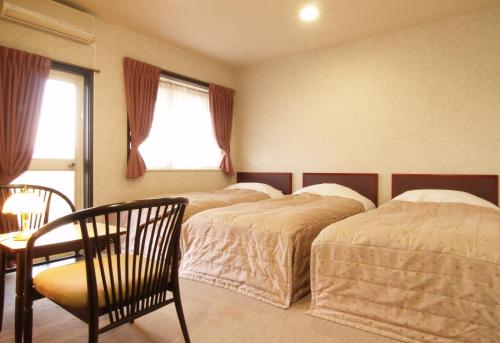 妙高赤仓宾至酒店的一间卧室设有两张床、一张桌子和一个窗口