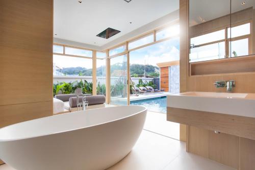 卡马拉海滩Himmapana Villas - SHA Extra Plus的一个带游泳池的浴室内的一个大型白色浴缸