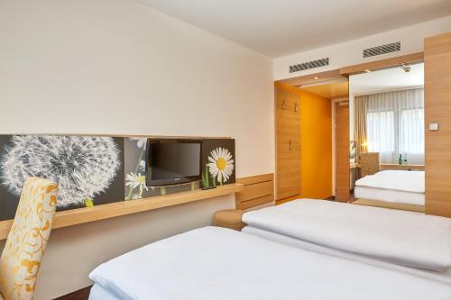 苏黎世苏黎世H+酒店 的一间卧室配有两张床和一台平面电视