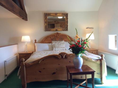 伊姆Bretton Cottage的一间卧室配有一张木床,桌子上放着花瓶