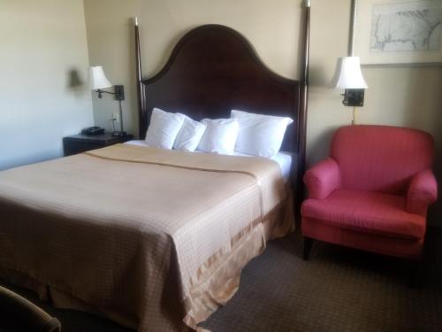 文特沃思港桑林酒店的酒店客房,配有一张床和一张红色椅子
