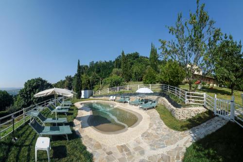 Mondaino特纳塔圣阿伯林度假屋的享有带椅子和遮阳伞的游泳池的景致。