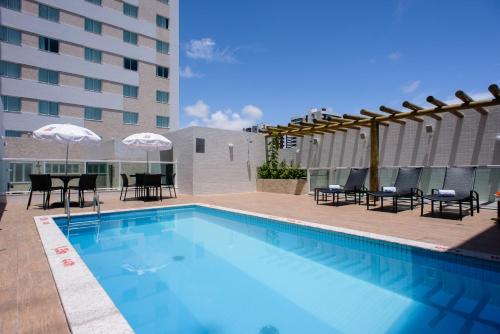 阿拉卡茹阿拉卡茹格因酒店的一座带椅子和遮阳伞的游泳池位于一座建筑旁边