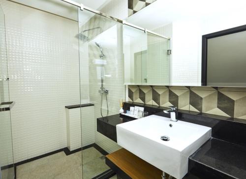 芭堤雅市中心芭堤雅切佐酒店的一间带水槽和玻璃淋浴的浴室