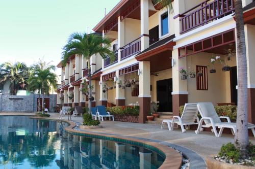 七岩Organgrinder Thai Paradise South的大楼前设有游泳池的酒店