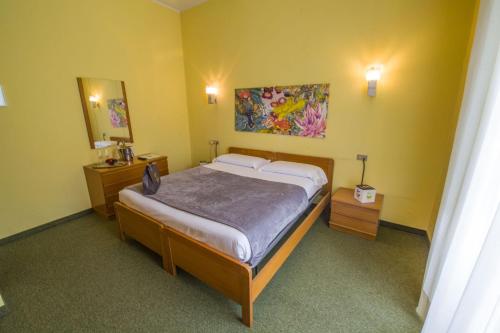 圣佩莱格里诺温泉比吉奥酒店的卧室配有一张床,墙上挂有绘画作品