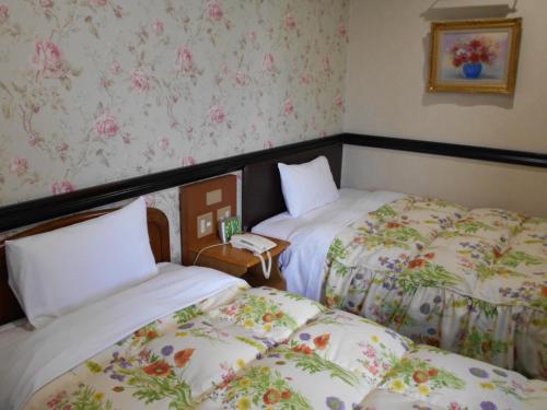 川口市Nishikawaguchi Station Hotel Stay Lounge的花卉壁纸客房内的两张床